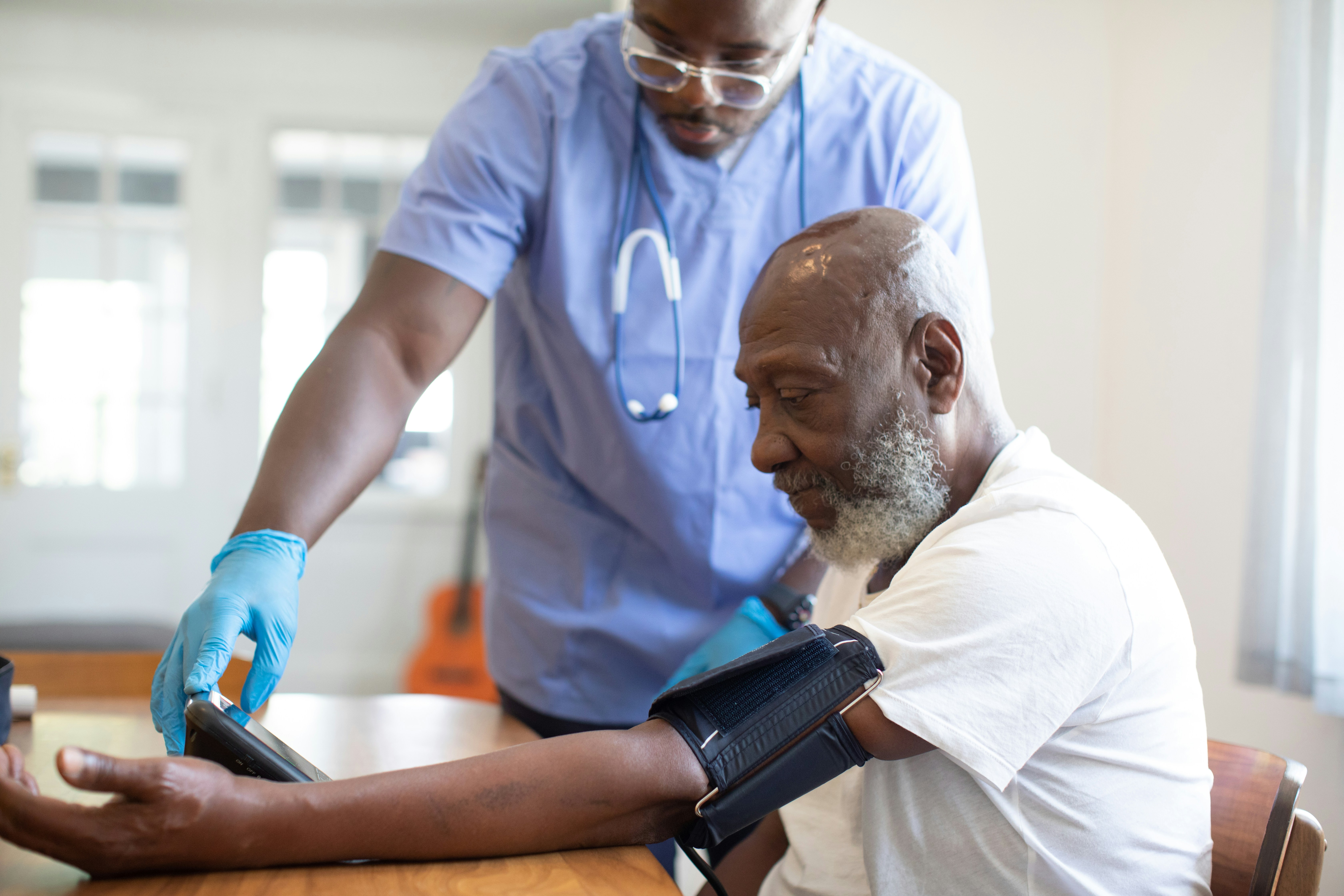 A clinician measures an older man's blood pressure during an annual wellness visit at a family medicine clinic.